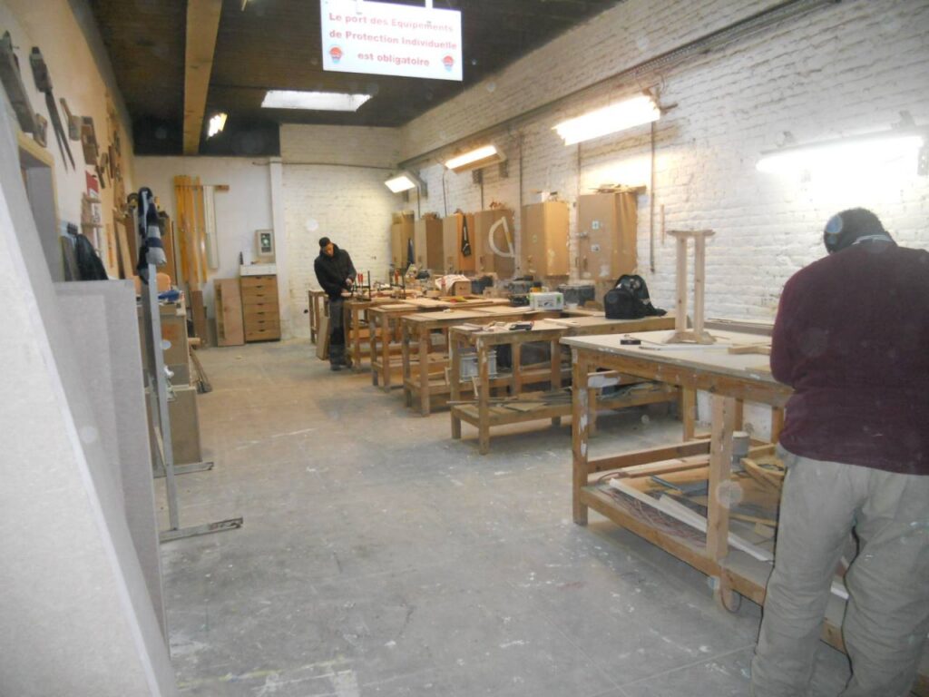 Stagiaires en formation dans l’atelier de menuiserie de l’asbl Boulot à Bruxelles, en train de travailler sur des établis.